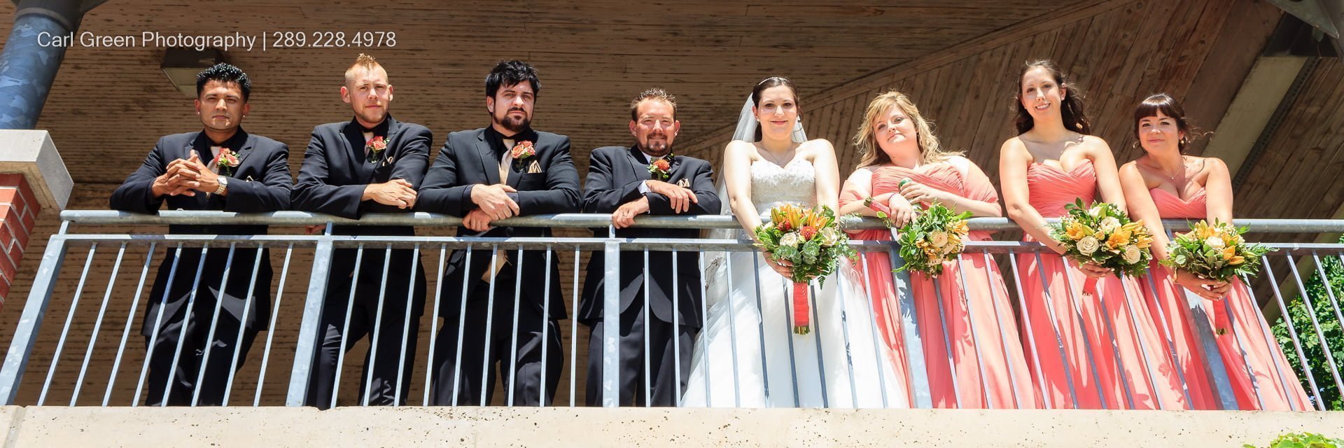 Wedding party on balcony looking at photographer