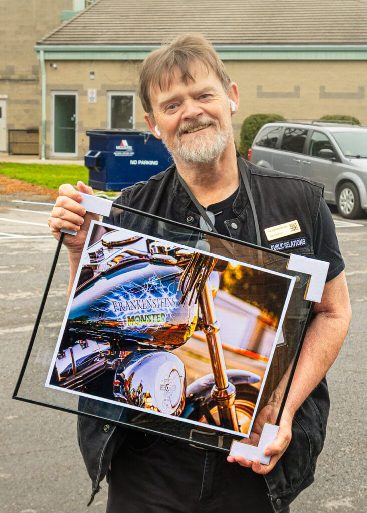 Carl holding a framed print of a motorbike