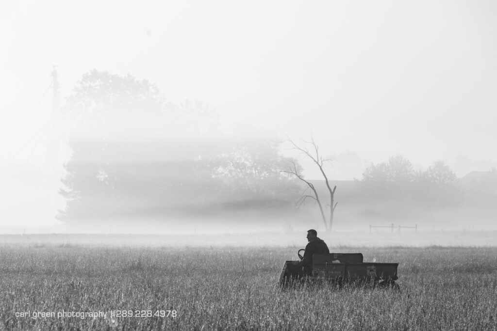 A farmer relaxing on a machine at sunrise